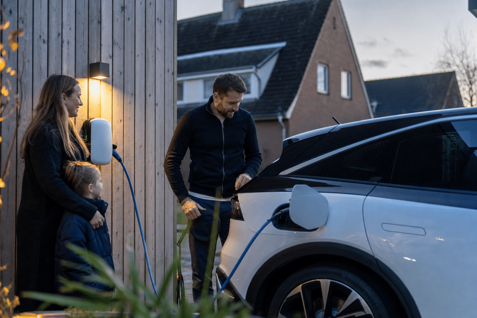 Familie lädt ihr Elektroauto abends vor dem Eigenheim an einer Wallbox