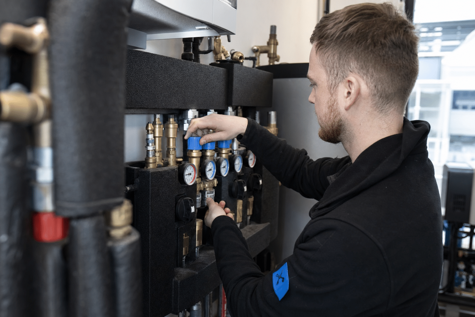 Monteur stellt im Heizungsraum den hydraulischen Abgleich an einem Heizkreisverteiler ein