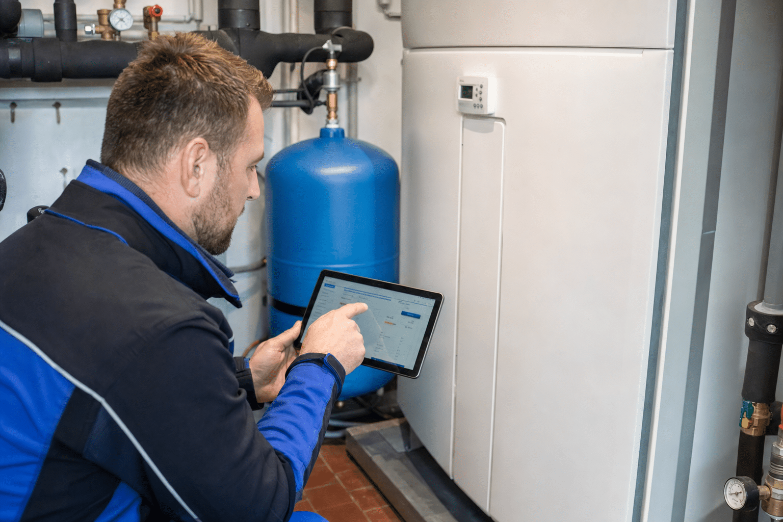 Servicetechniker prüft im Heizungsraum die Messwerte einer installierten Wärmepumpe